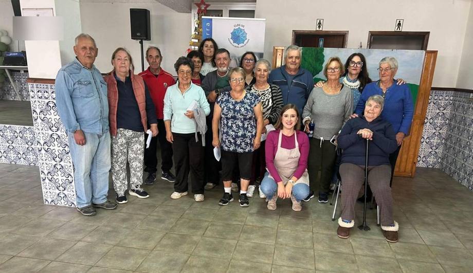 Foto de grupo com os participantes do workshop e a Andreia, junto ao roll-up do CLDS 5G