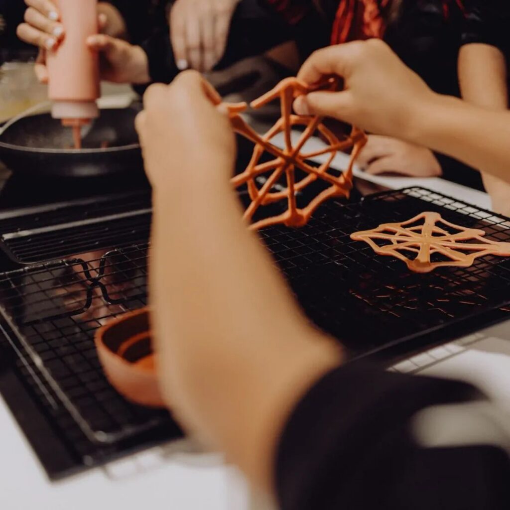 Criança a fazer teias de aranha de panqueca para o Halloween