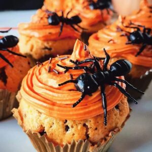 Cupcakes de formiga para o Halloween com cobertura laranja e aranhas